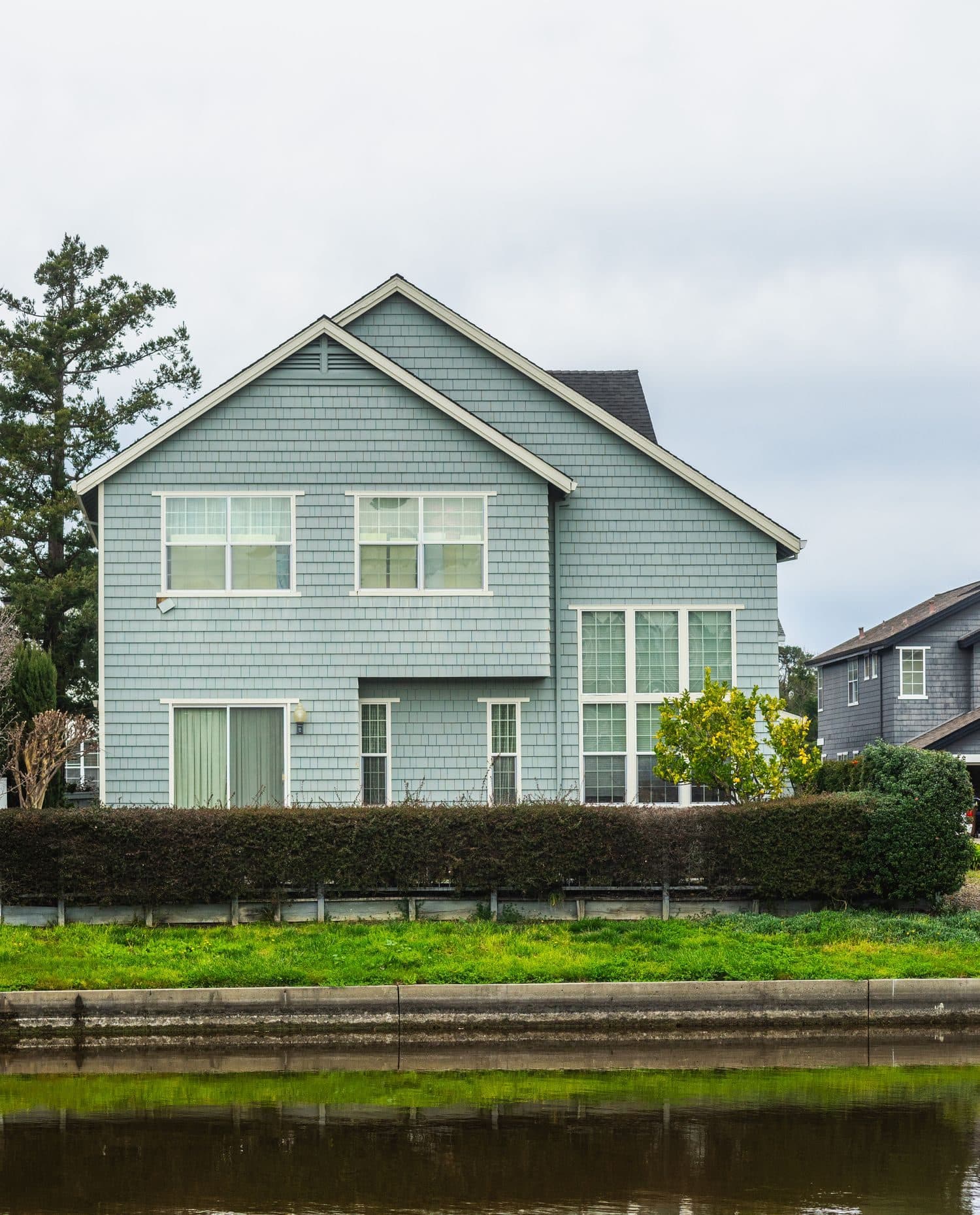 A two-storey shingled home with white-framed windows across the front