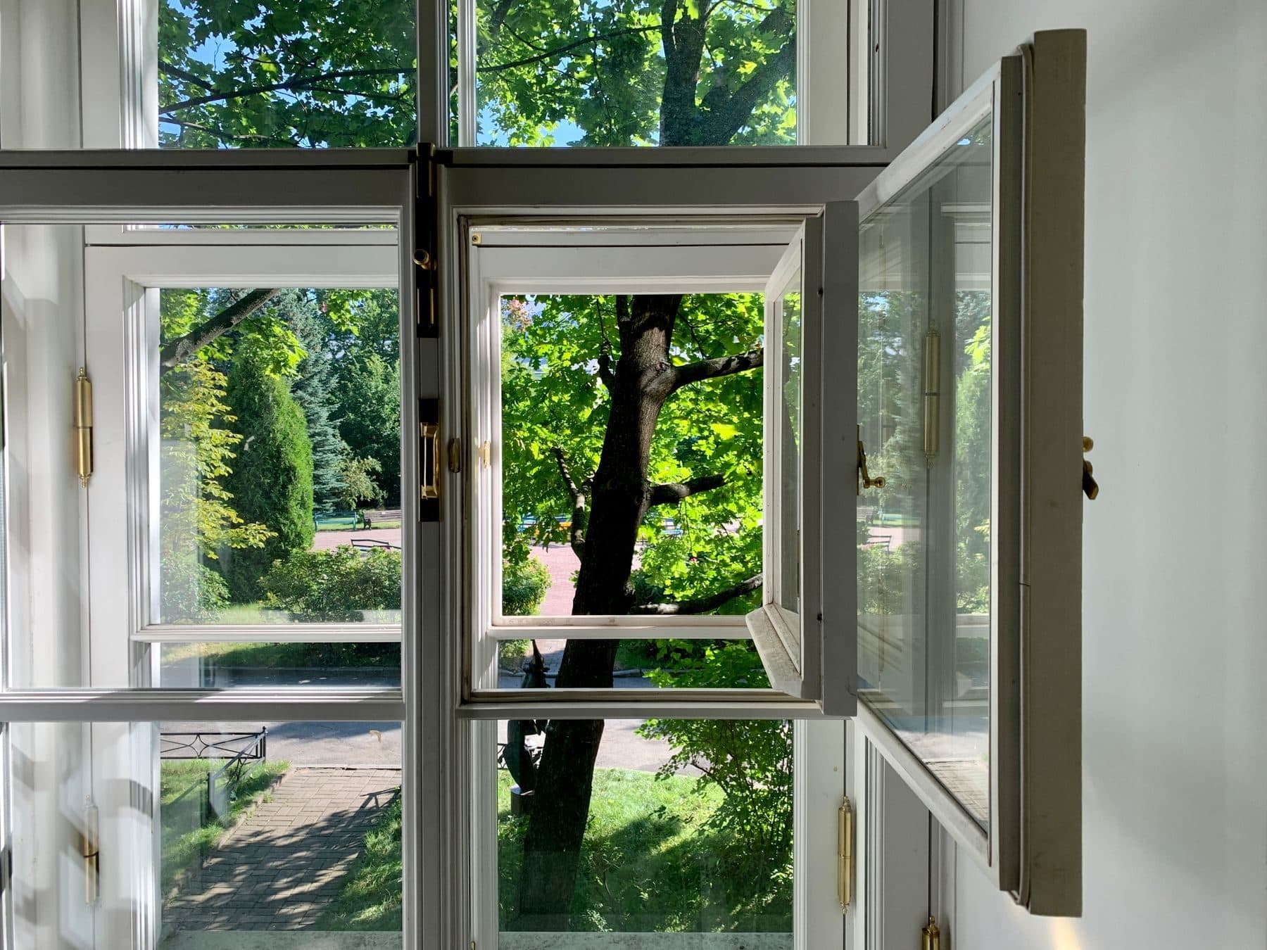 New white casement windows standing open onto a green garden